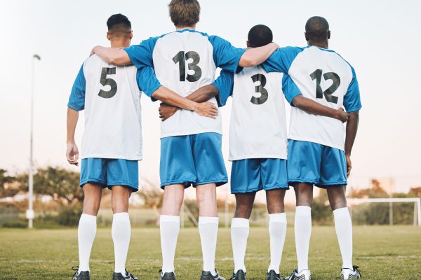 Soccer, team and hug standing with back on the field in partnership, trust or ready for sports game or match. Sport men hugging in teamwork, collaboration or unity for fitness, training or workout.